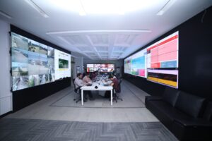 3 Huge indoor SMD screens displaying some data and images. With some people sitting in front of these screens. This complete solutions provided by EziSol.
